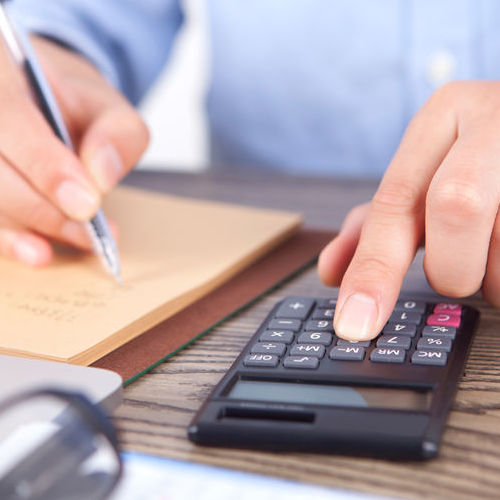Man balancing budget with calculator indicative of financing.